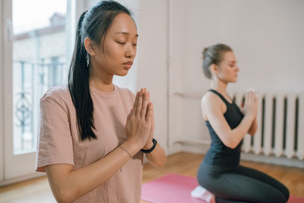 Two women with eyes closed in a calm mindfulness moment indoors