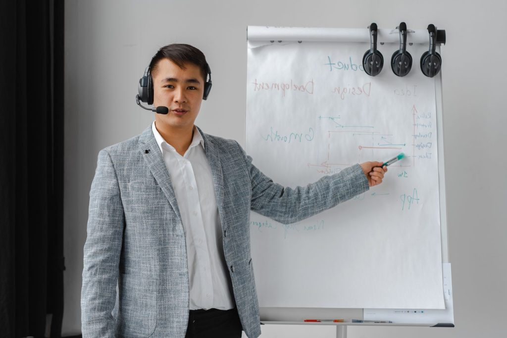 Presenter in a grey blazer writing on a flipchart