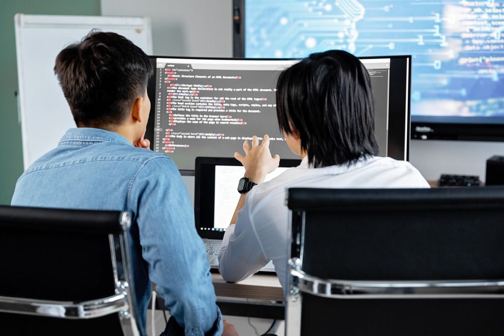 Two colleagues reviewing code on large monitors