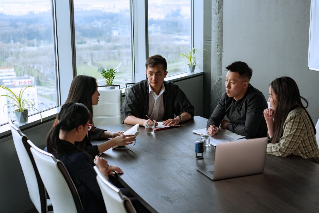 Colleagues around a meeting table beside a window