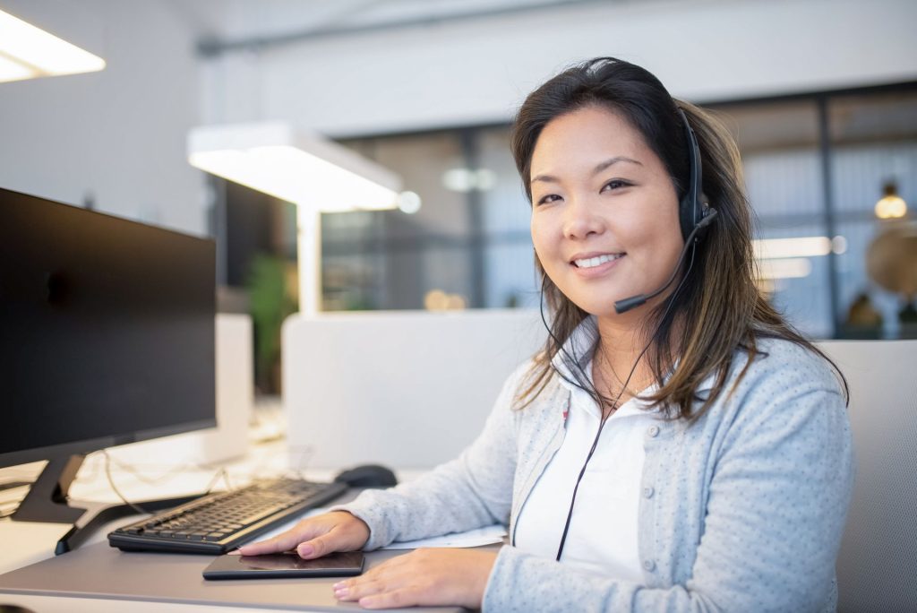 Smiling customer service agent wearing a headset at her desk